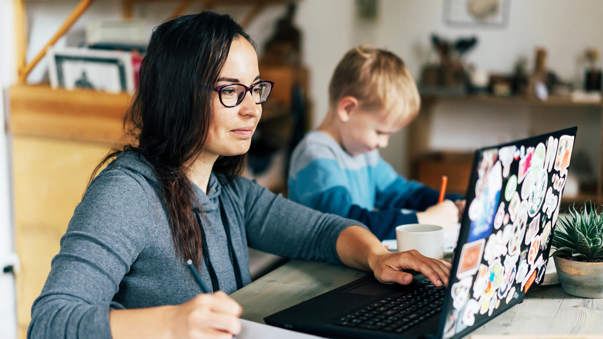 Young woman at laptop with child sitting next to her