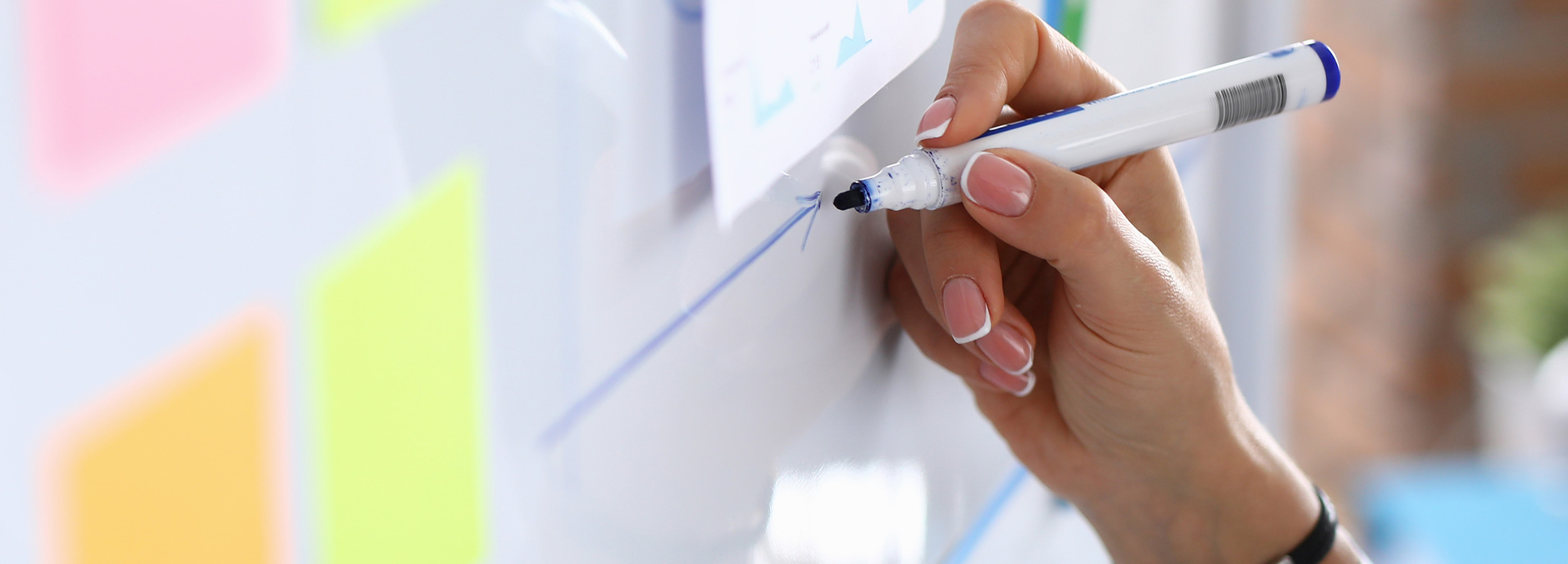 Close up of woman's hand writing on white board