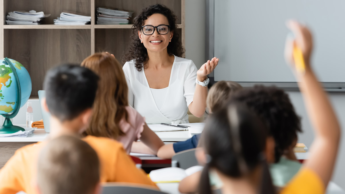 teacher at desk with students